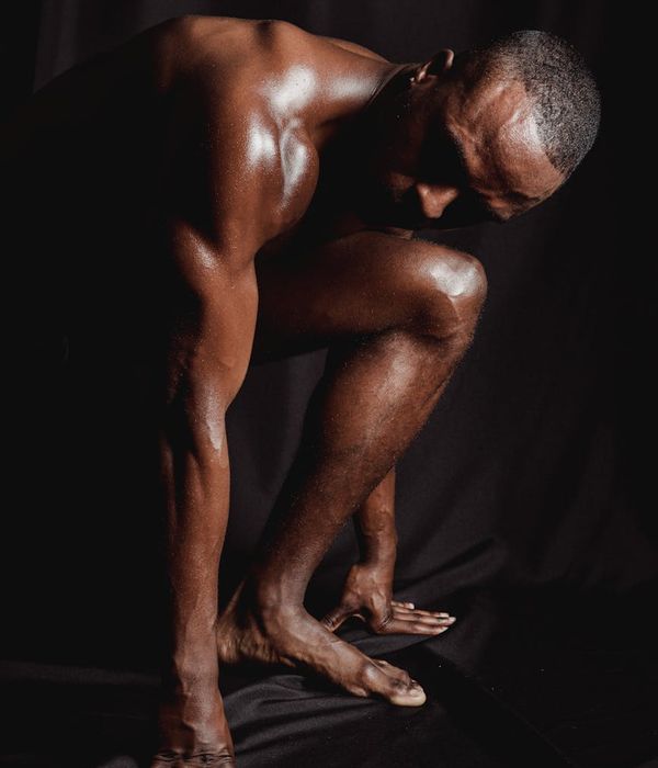 Man executing a difficult balance and strength pose in a minimalist setting.